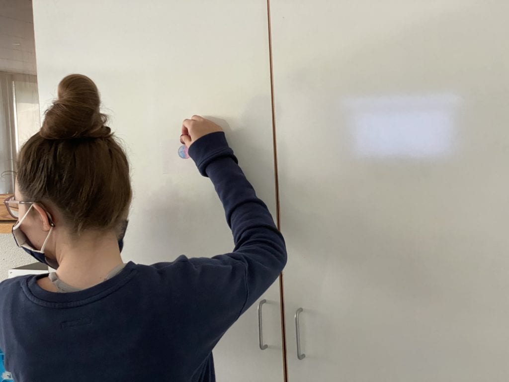 student hanging up drawing