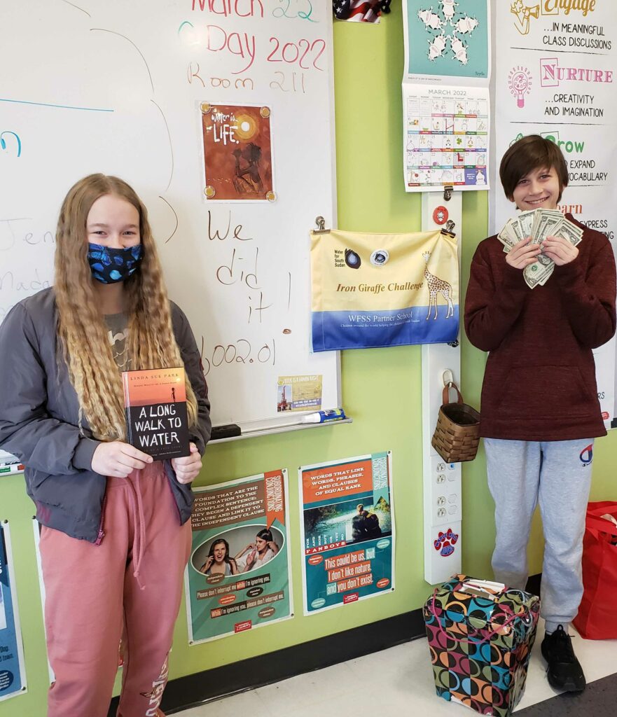 Seventh grade students hold fundraiser money and a book