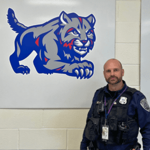Image of Schodack Police Officer Rich Eckel standing next to district logo.