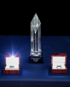 Close-up of the NYSPHSAA Hall of Fame Class of 2026 crystal award for Coach Dan Gillespie, flanked by two open ring display boxes.